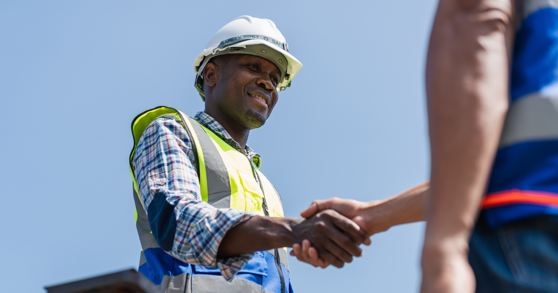WJN case study cropped A construction worker smiles as he shakes hands with a fellow worker.